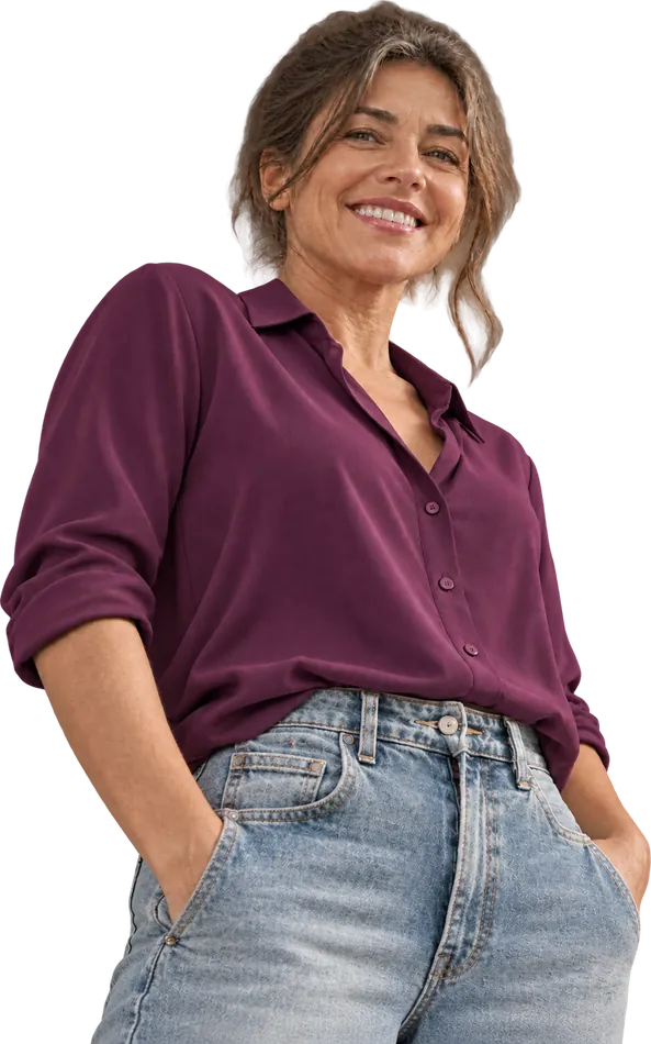 Smiling woman in midlife wearing a plum shirt and jeans, hands in her pockets